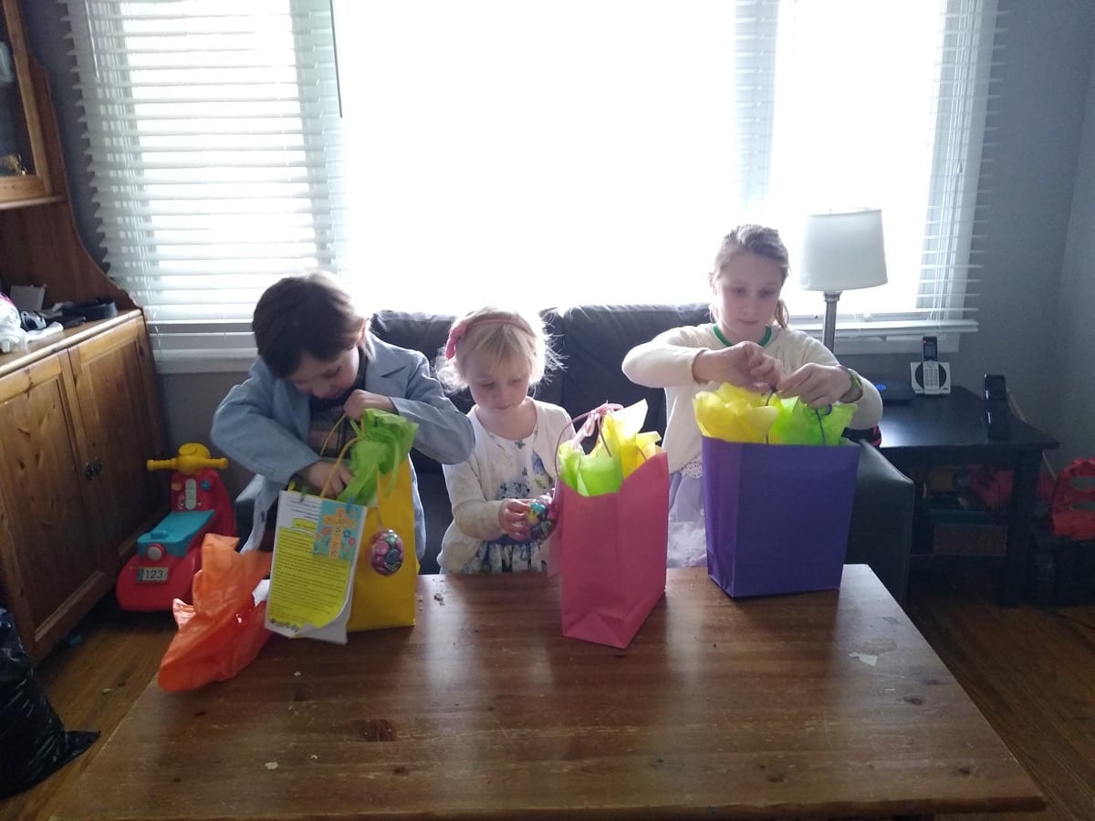Easter Sunday school treats from Jan were delivered the Parish Kids this year by car and left at their front door. Jillian, Charlotte and Jackson are opening their goody bags.