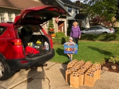 Eileen Martin, a volunteer from Anglicans in Action, and her grandson load bags for delivery to Community Care. Photo: Contributed by Diane Kidson.