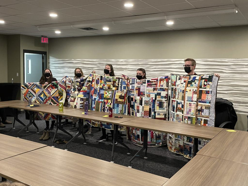 Students hold up gifted quilts.